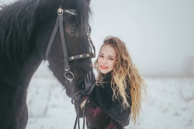 Kışın bir alanda bir at ile kız