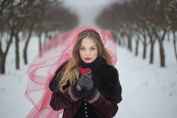 Chica en un velo rojo en la nieve en el invierno — Foto de Stock