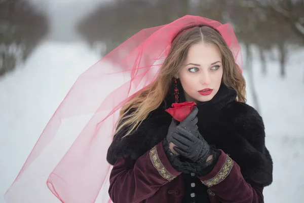 Meisje in een rode sluier in de sneeuw in de winter — Stockfoto