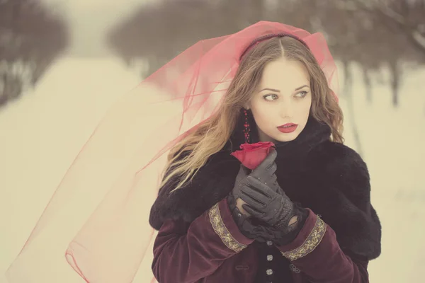 Fille dans un voile rouge sur la neige en hiver — Photo