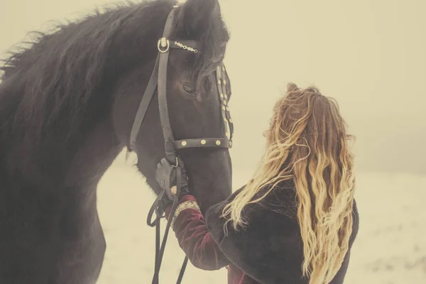 A girl with a horse in a field in winter — Stock Photo, Image