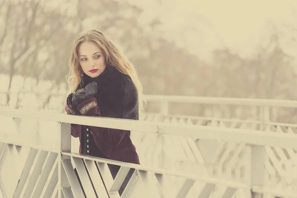 Hermosa chica de pie en el puente peatonal en invierno — Foto de Stock