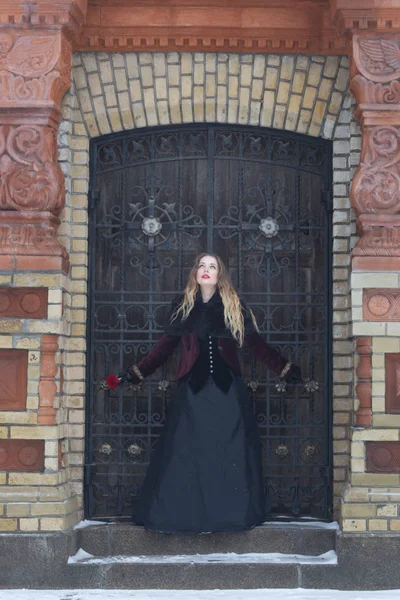 A beautiful girl standing at the lattice wrought — Stock Photo, Image