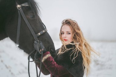 Kışın bir alanda bir at ile kız