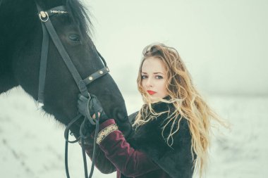 Kışın bir alanda bir at ile kız