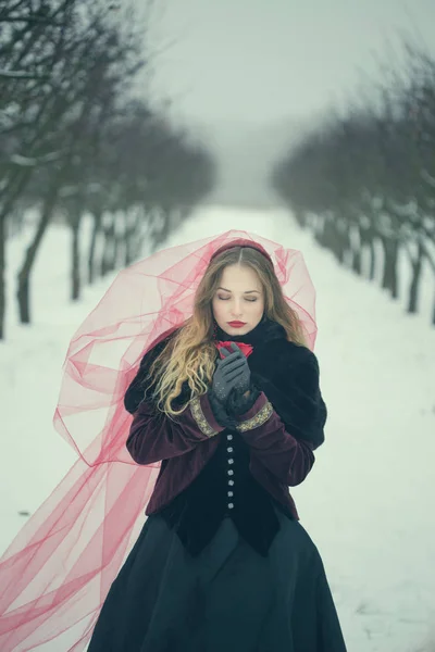 Chica en un velo rojo en la nieve en el invierno — Foto de Stock