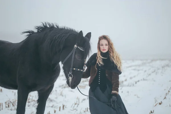 Een meisje met een paard in een veld in de winter — Stockfoto