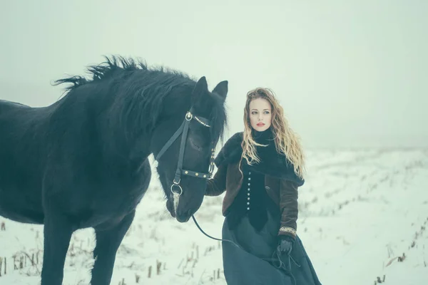 Een meisje met een paard in een veld in de winter — Stockfoto