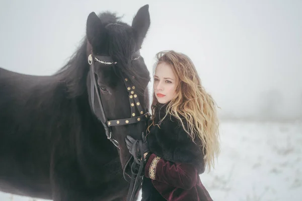 Una chica con un caballo en un campo en invierno — Foto de Stock