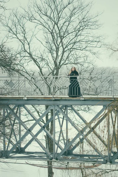Mooi meisje permanent op de voetgangersbrug in de winter — Stockfoto