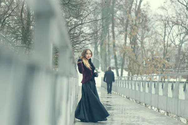 Hermosa chica de pie en el puente peatonal en invierno — Foto de Stock