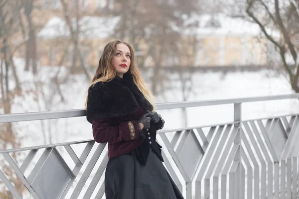 Hermosa chica de pie en el puente peatonal en invierno — Foto de Stock