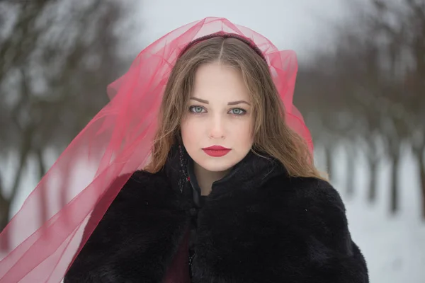 Chica en un velo rojo en la nieve en el invierno — Foto de Stock