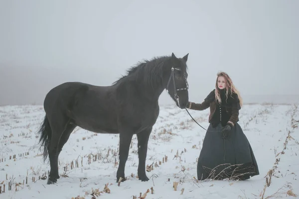 Una chica con un caballo en un campo en invierno — Foto de Stock