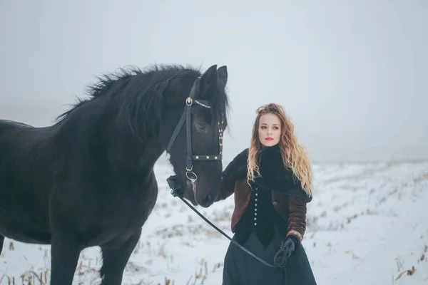 Een meisje met een paard in een veld in de winter — Stockfoto