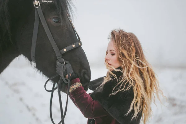 Een meisje met een paard in een veld in de winter — Stockfoto
