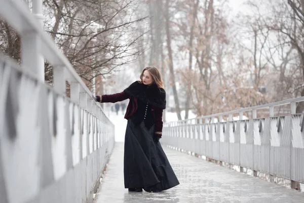 Schönes Mädchen, das im Winter auf der Fußgängerbrücke steht — Stockfoto