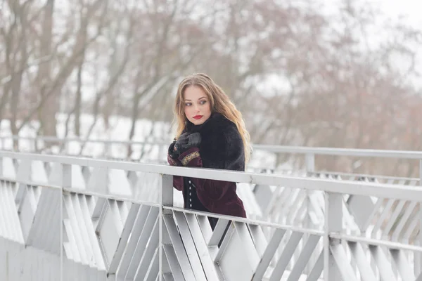 Vacker flicka som står på gångbron på vintern — Stockfoto