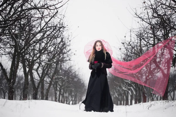 Flicka i en röd slöja på snön på vintern — Stockfoto