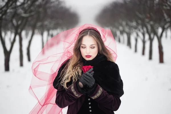 Flicka i en röd slöja på snön på vintern — Stockfoto