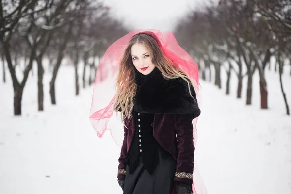 Mädchen im roten Schleier auf dem Schnee im Winter — Stockfoto
