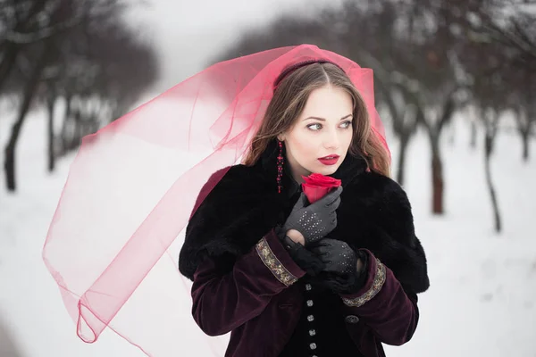 Κορίτσι σε ένα κόκκινο πέπλο πάνω στο χιόνι το χειμώνα — Φωτογραφία Αρχείου