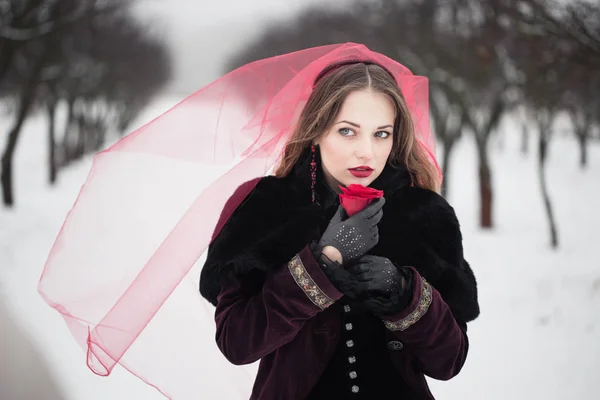 Chica en un velo rojo en la nieve en el invierno — Foto de Stock