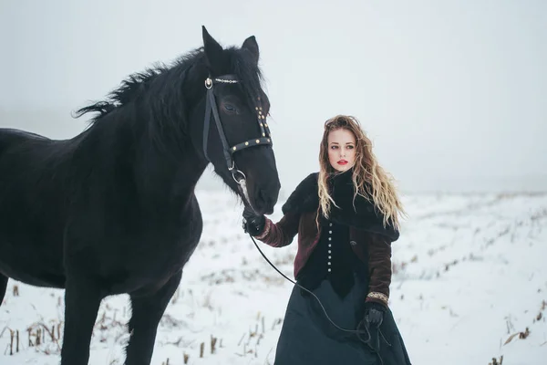 Een meisje met een paard in een veld in de winter — Stockfoto