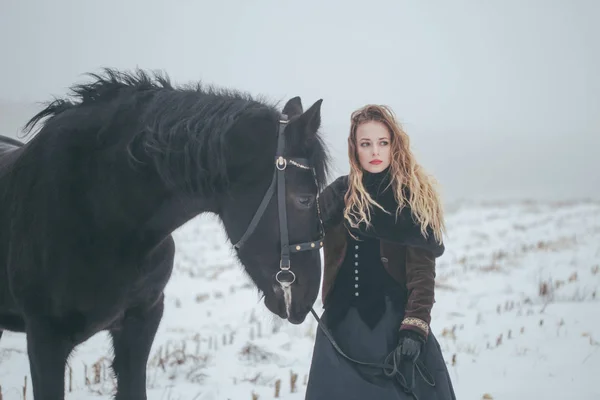 Een meisje met een paard in een veld in de winter — Stockfoto