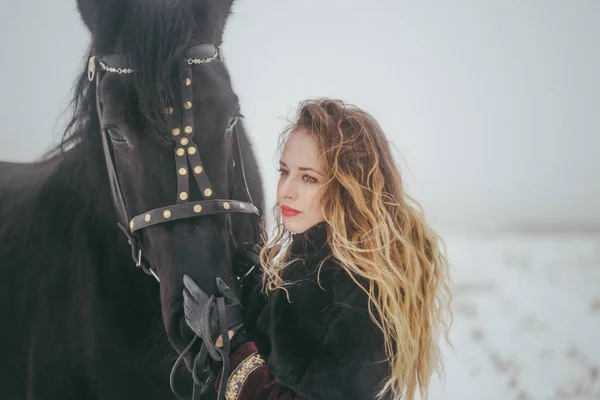 Een meisje met een paard in een veld in de winter — Stockfoto