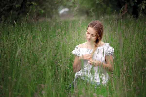 屋外の芝生の上に座っている短パンでブロンドの女の子 — ストック写真