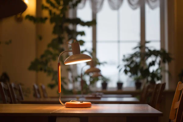 Lendo na mesa com uma lâmpada na biblioteca — Fotografia de Stock