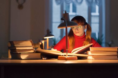 lambanın altında kütüphanede kitap okuyarak kız