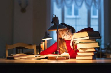 lambanın altında kütüphanede kitap okuyarak kız