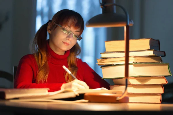 Menina lendo um livro na biblioteca sob a lâmpada — Fotografia de Stock