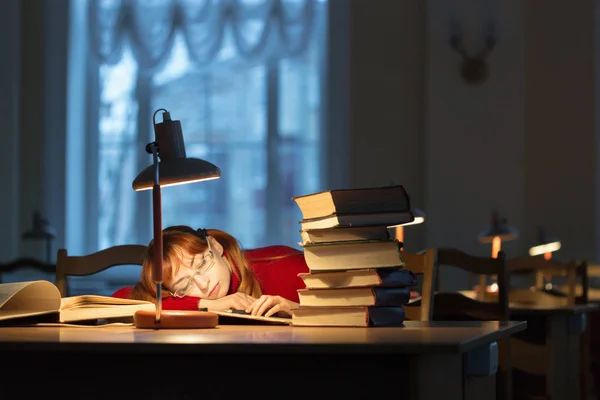 girl reading a book in the library under the lamp