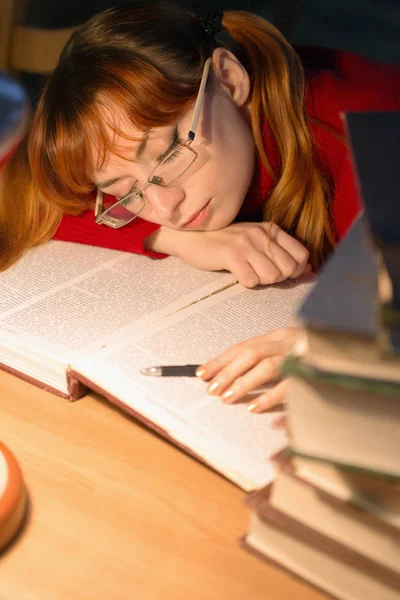लड़की दीपक के नीचे पुस्तकालय में एक किताब पढ़ रही है — स्टॉक फ़ोटो, इमेज
