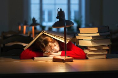 lambanın altında kütüphanede kitap okuyarak kız