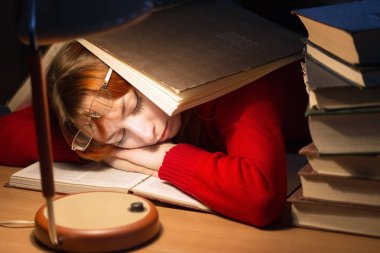 lambanın altında kütüphanede kitap okuyarak kız