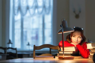 lambanın altında kütüphanede kitap okuyarak kız