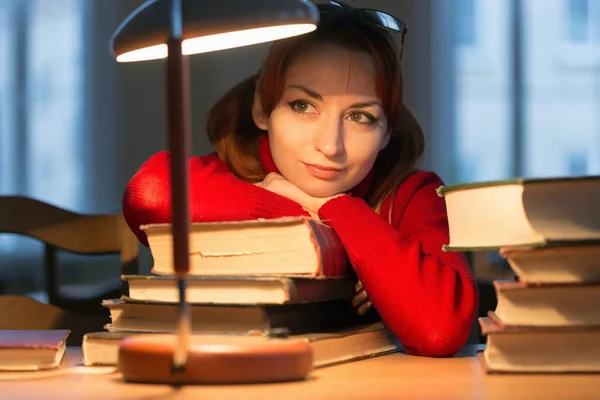 Dívka s knihou v knihovně pod lampou — Stock fotografie