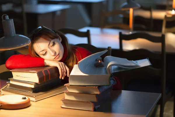 Meisje het lezen van een boek in de bibliotheek onder de lamp — Stockfoto