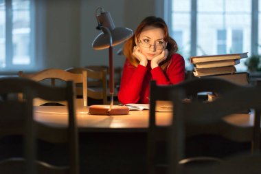 lambanın altında kütüphanede kitap okuyarak kız