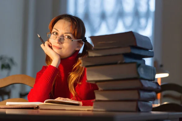 Девушка читает книгу в библиотеке под лампой — стоковое фото
