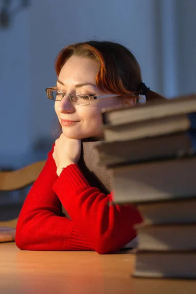 Menina lendo um livro na biblioteca sob a lâmpada — Fotografia de Stock