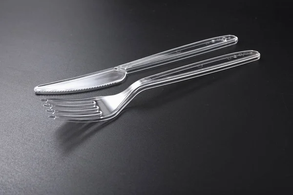 Jednorázové plastové nádobí. vidlička a nůž na černém pozadí. — Stock fotografie