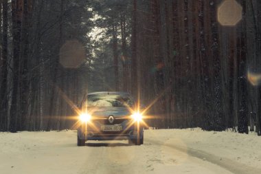 Gomel, Belarus - 21 Şubat 2017: Araba Renault - Logan farlar ile kış ormandaki.
