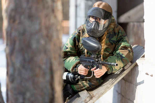 Chica jugando paintball en overoles con un arma . —  Fotos de Stock