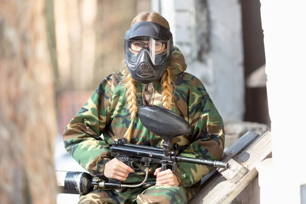 Chica jugando paintball en overoles con un arma . —  Fotos de Stock