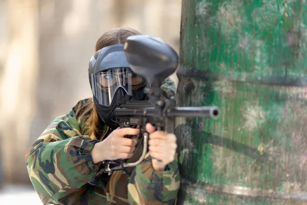 Girl playing paintball in overalls with a gun. — Stock Photo, Image